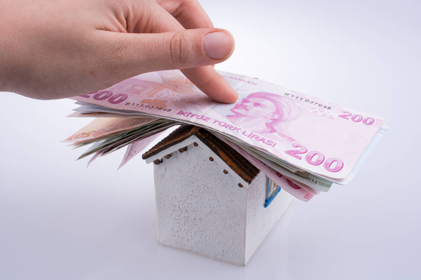 Hand met Turkse Lira biljetten op het dak van een huis model - Foto, afbeelding