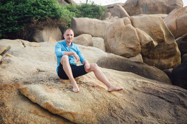 Young boy in blue t-shirt at the ocean beach with big stones - Фото, зображення