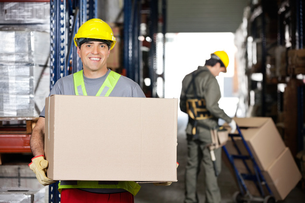 Mid Adult Foreman With Cardboard Box At Warehouse - 写真・画像