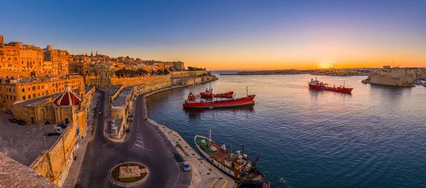 Valletta, Malta - Panoramic shot of an amazing summer sunrise at Valletta's Grand Harbor with ships and the ancient houses and walls of the maltese capital city. - Photo, Image