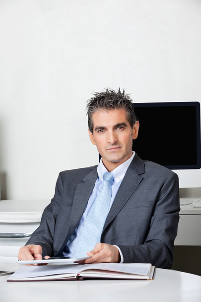 Businessman With Digital Tablet Sitting At Desk - Foto, afbeelding