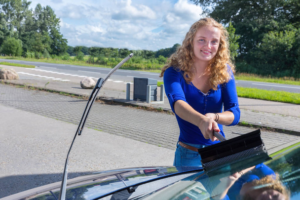 Fiatal holland nő mosás autó szélvédő - Fotó, kép