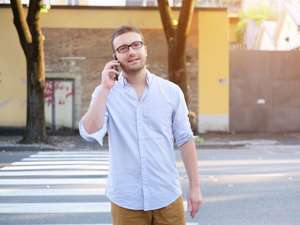 Мужчина звонит на свой смартфон и гуляет по улицам города
 - Фото, изображение