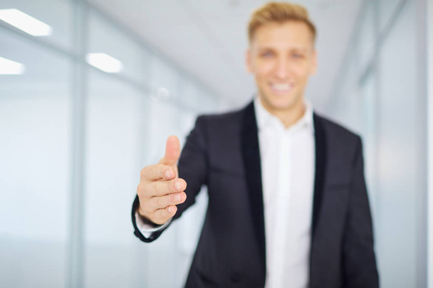 Concept welcome. Businessman holds out his hand and smiling in a - Fotoğraf, Görsel