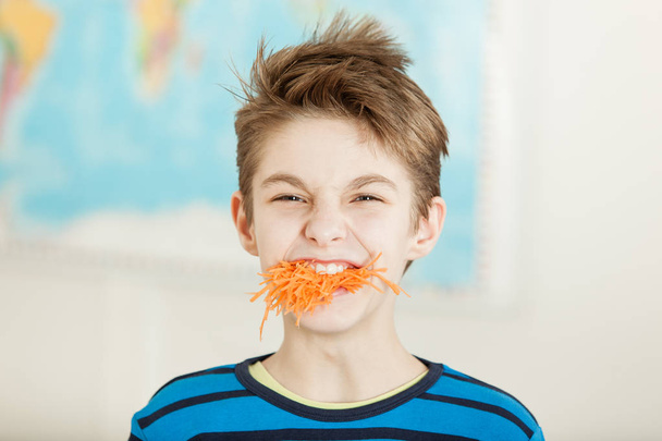 Young boy with a mouthful of grated carrot - Photo, Image