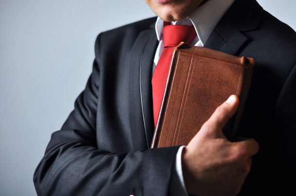 Businessman in a suit holding a book - Fotó, kép