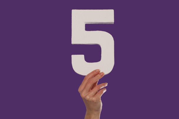weibliche Hand hält die Zahl 5 von unten hoch - Foto, Bild