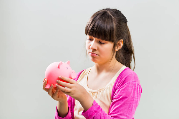 Sad little girl holding piggy bank - Φωτογραφία, εικόνα