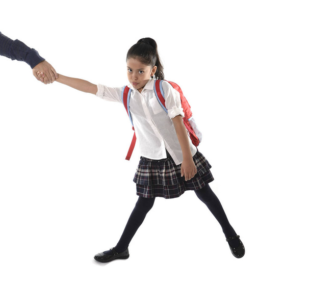 батькова рука тримає і тягне свою молоду примхливу латинську школярку з уніформою і рюкзаком сердитий
 - Фото, зображення
