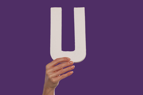 γυναικείο χέρι που κρατά ψηλά το γράμμα u από το κάτω μέρος - Φωτογραφία, εικόνα
