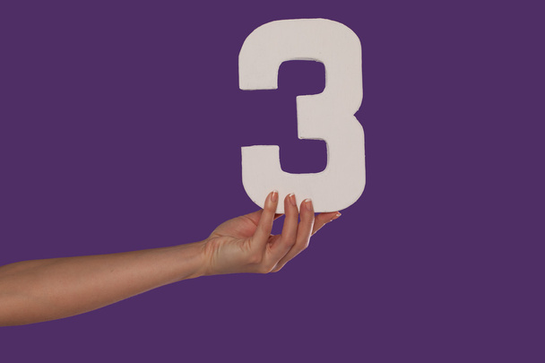 Mano femenina sosteniendo el número 3 desde la izquierda
 - Foto, Imagen