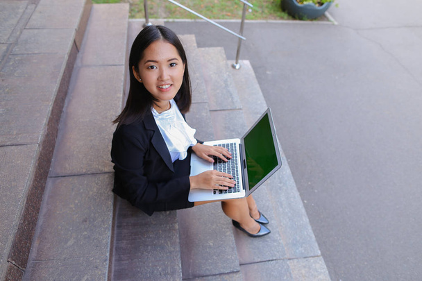 Asiática hermosa joven hembra sostiene en las manos ordenador portátil y sonriendo, l
 - Foto, imagen