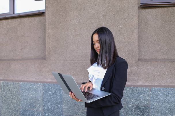 schöne junge Unternehmerin hält Laptop und arbeitet, löst - Foto, Bild