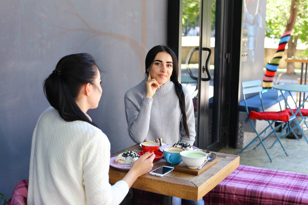 drei schöne Frauen lächeln im Café, reden, erzählen Geheimnisse, essen, d - Foto, Bild