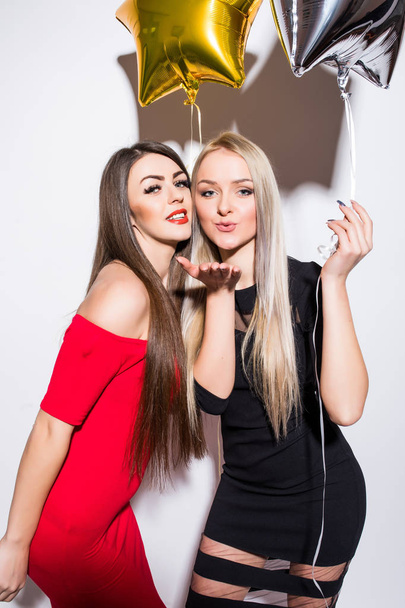 Two smiling cute young women  with balloons send kisses. - Fotografie, Obrázek
