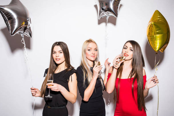 Wesoły młodych kobiet picie szampana, rozmawiając i śmiejąc się z balonów na party - Zdjęcie, obraz