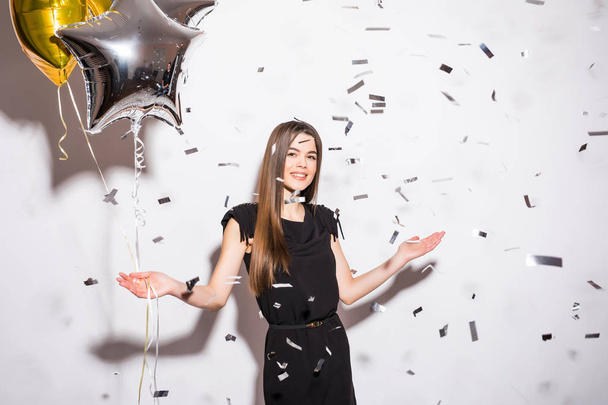 Молодая женщина держит звездный шар с мухой конфетти на вечеринке
 - Фото, изображение