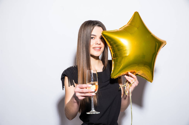 Szczęśliwy atrakcyjna młoda kobieta w czarnej sukni, trzymając gwiazda w kształcie balon i picia szampana - Zdjęcie, obraz