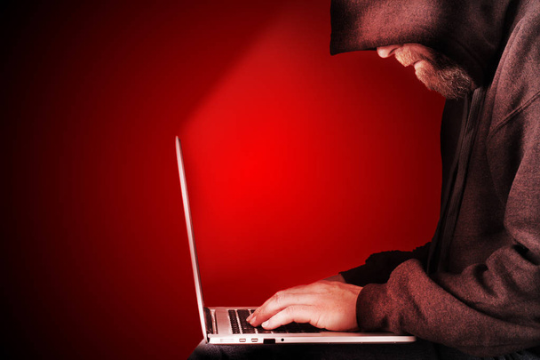 Hooded computer hacker rode achtergrond - Foto, afbeelding
