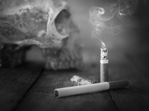 Still life κρανίο και το τσιγάρο καίγεται με τον καπνό, σε ξύλο. - Φωτογραφία, εικόνα