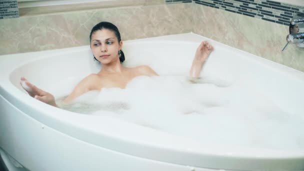 Meisje in een bubbelbad ontspant en stort in het water - Video
