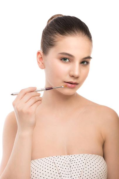 Young brunette woman with clean face. Girl perfect skin applying cosmetic brush. Isolated on a white. - Photo, image