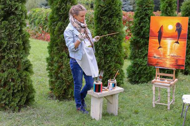 Művész nő tart festés és ránéz, pózol a kamera egy - Fotó, kép