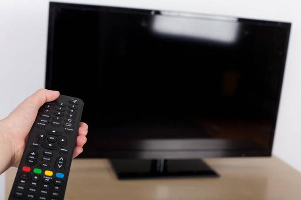 Hand using remote control turned off on the TV - Φωτογραφία, εικόνα