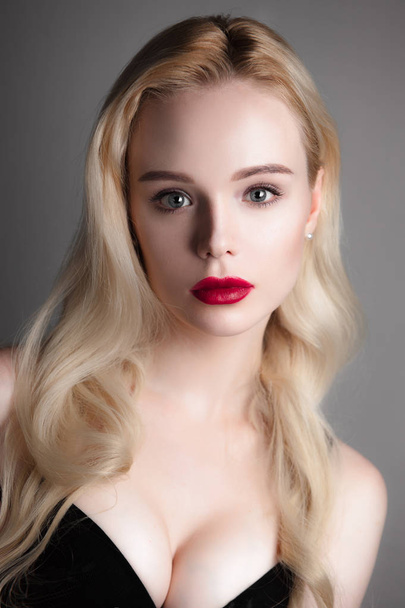Beauty model girl with perfect make-up red lips and blue eyes looking at camera, wearing black bra. Portrait of attractive sexy young woman with blond hair. Beautiful female face with clear fresh skin - Фото, изображение