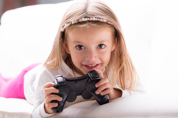 Παιχνιδιάρικο το χαριτωμένο μικρό κορίτσι με έναν ελεγκτή παιχνιδιών - Φωτογραφία, εικόνα
