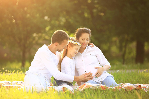 happy father of a daughter and a pregnant mom at a picnic - Fotó, kép