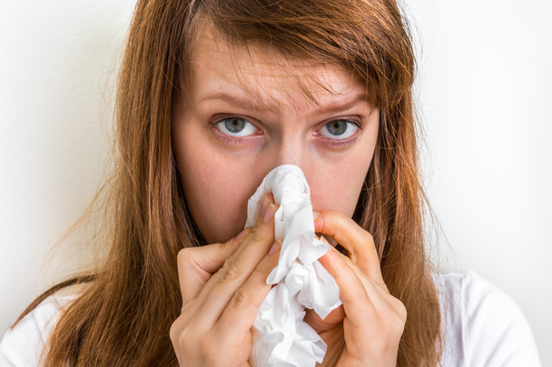 Woman with allergy or flu cold symptoms sneezing in tissue - Photo, Image
