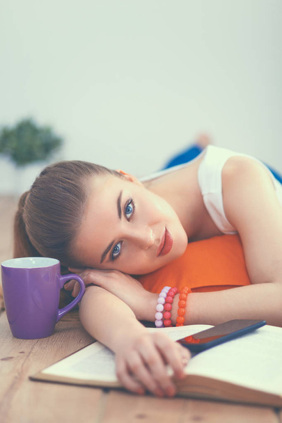 Smiling young woman lying on a white floor with pillow - Foto, imagen