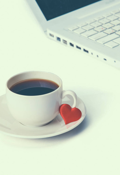 Laptop or notebook with cup of coffee and heart on table - Foto, afbeelding
