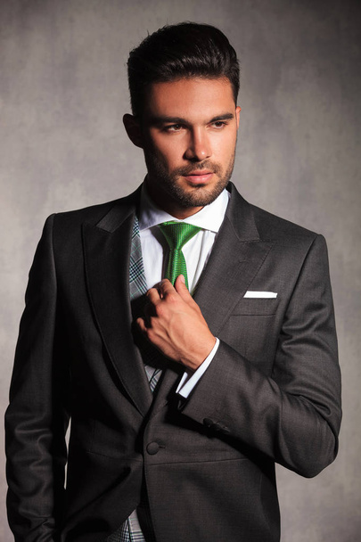 portrait of sexy young man in tuxedo correcting his tie  - Fotoğraf, Görsel