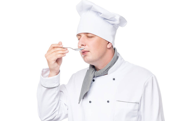 chef con una cuchara de metal prueba la sopa sobre un fondo blanco
 - Foto, imagen