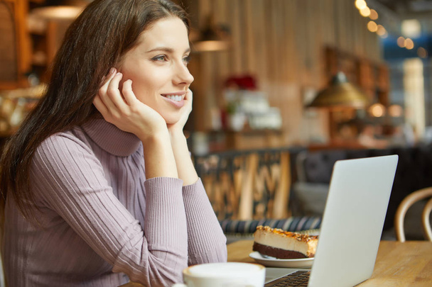 Beautiful brunette using laptop in cafe - Фото, зображення