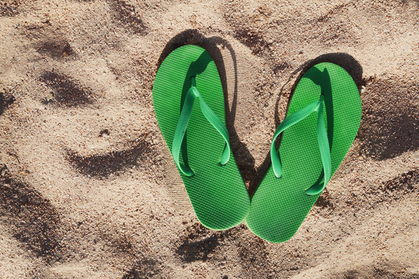 zöld flip papucs a homok, a tenger közelében - Fotó, kép