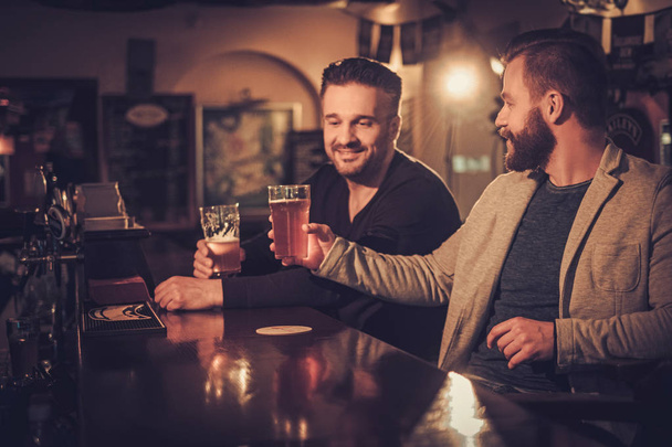 De vieux amis joyeux buvant de la bière pression au comptoir du bar au pub
. - Photo, image