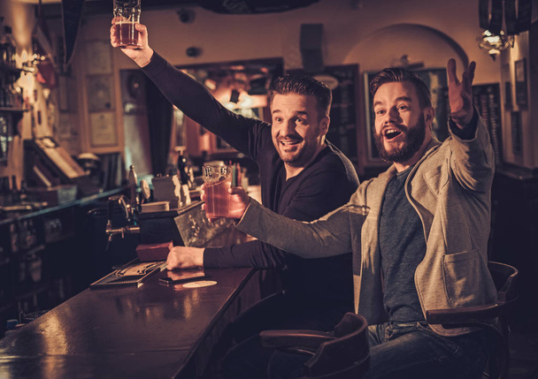 Wesoły starych znajomych, pije piwo w barze licznika w pubie. - Zdjęcie, obraz