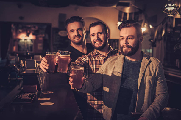 Allegro vecchi amici che bevono birra alla spina al bancone del bar in pub
. - Foto, immagini