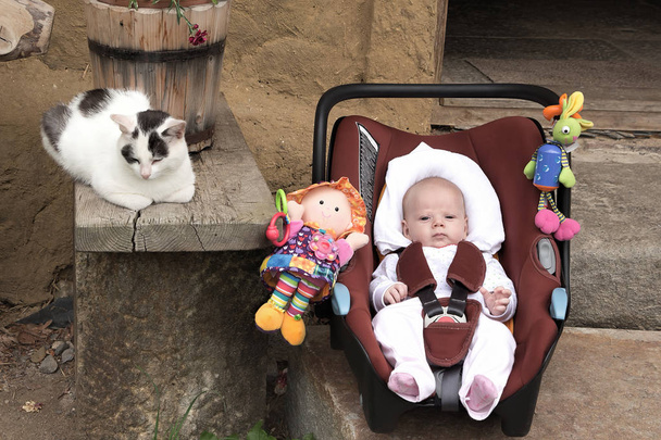 Jonge baby, baby in een baby-autostoeltje op een steenworp afstand van de oude tellen - Foto, afbeelding