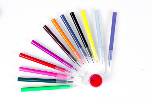 Marqueurs colorés disposés près des bocaux avec des peintures comme les rayons solaires. Papeterie sur fond blanc
. - Photo, image