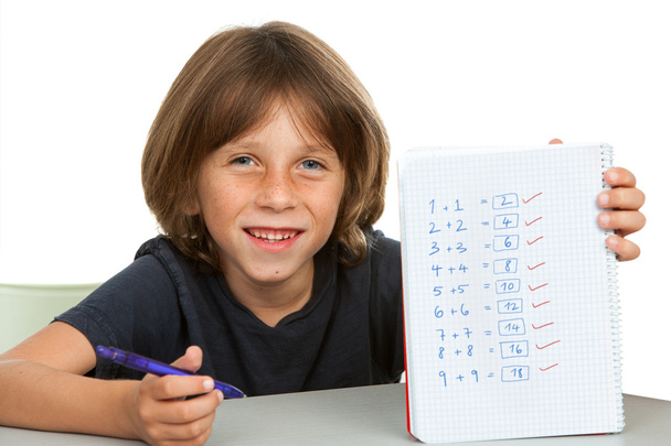 Lindo niño mostrando cuaderno con problemas matemáticos
. - Foto, Imagen