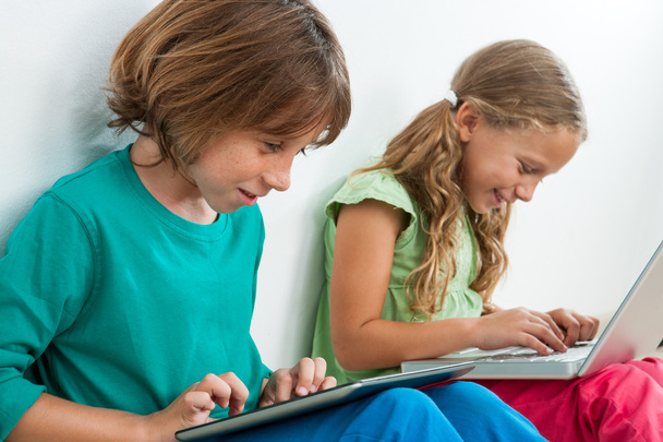 két gyerek játszik a tábla és a laptop. - Fotó, kép