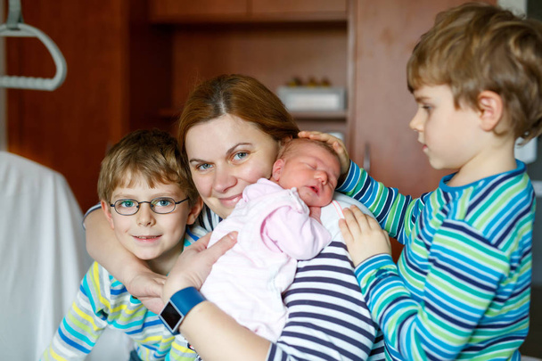 Mother holding newborn baby girl on arm with two kids boys - Fotografie, Obrázek