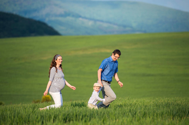 Young family on a walk against green fields and hills - Фото, зображення