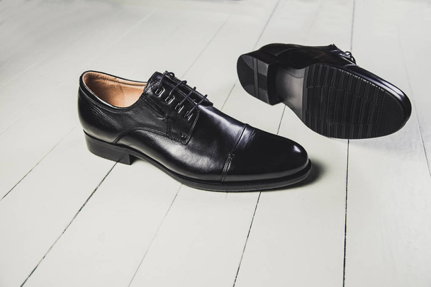 Чёрные мужские кожаные туфли на белой доске
 - Фото, изображение