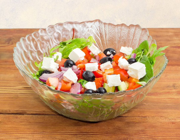 Griekse salade met glas slakom op houten oppervlak - Foto, afbeelding