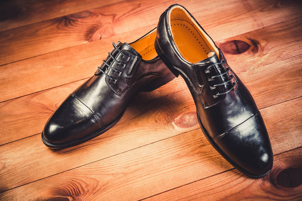 Black leather men's shoes on a wooden background - Фото, изображение